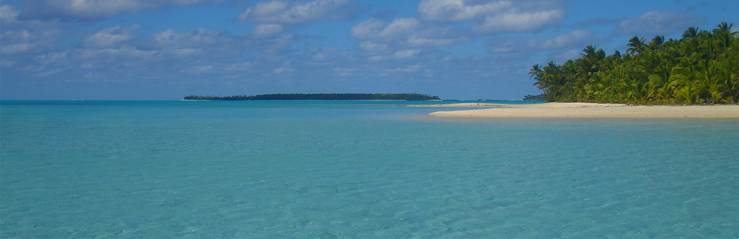 Sparkling azure water of Aitutaki lagoon with tropical island in background
