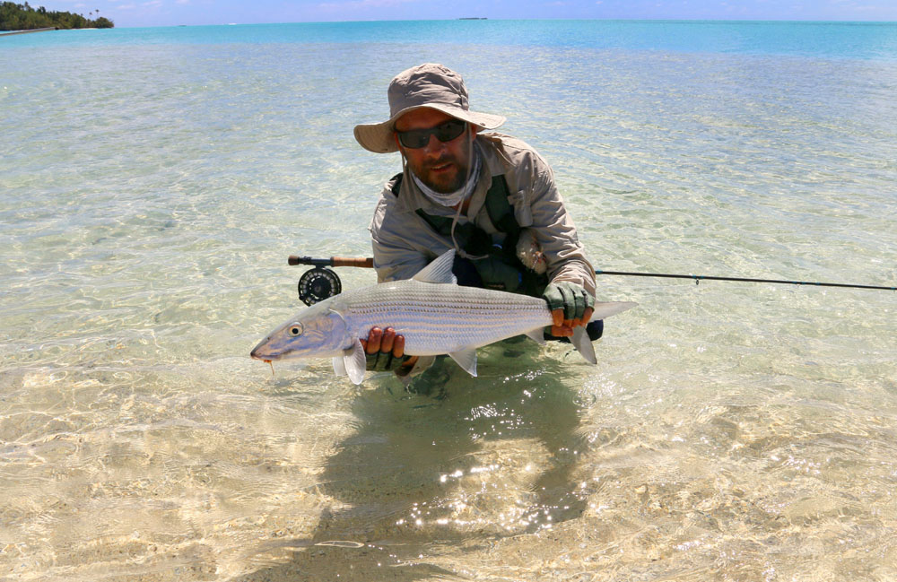 Fly fisherman holding bonefish about to be released in azure Aitutaki lagoon