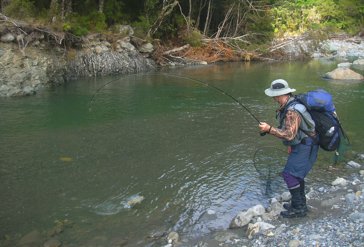 Fisherman on a New Zealand backcountry river, bringing in a trout, showinging strength and curve of bending TVO BVK 5wt fly fishing rod 