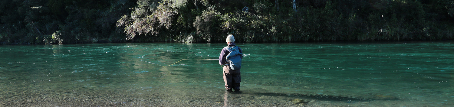 Fly fisherman trout spey casting in emerald river pool