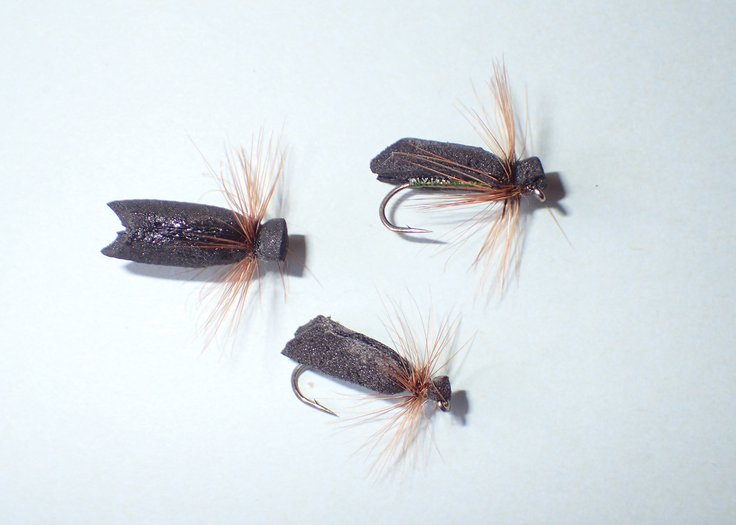 Three Scuttling Caddis dry flies on a plain background